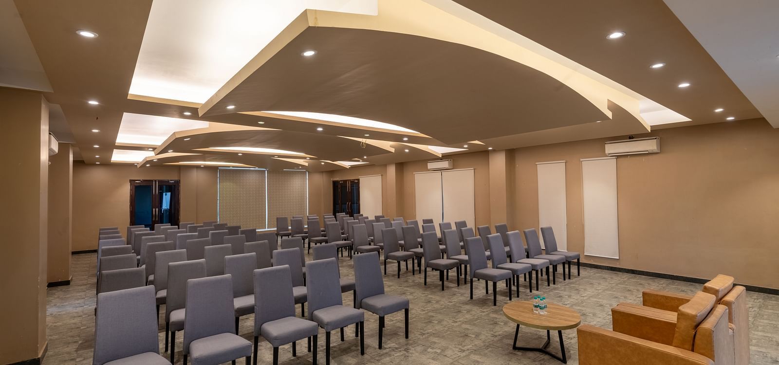 Banquet hall at DLS Forest Vines Resort, with cushioned seating arranged on both sides, a plush sofa, and a table placed in front.